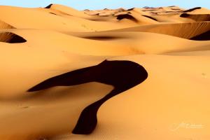 una duna de arena en el desierto con una silueta en Merzouga Desert camp, en Merzouga