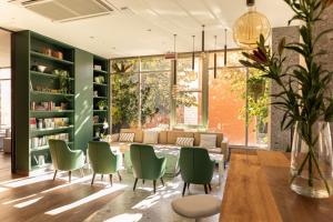 biblioteca con sedie verdi, tavolo e librerie di Bio Boutique Hotel XU' - Gruppo Ambienthotels a Rimini