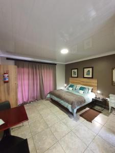 a bedroom with a bed and a pink curtain at Huis van Seisoene in Klerksdorp