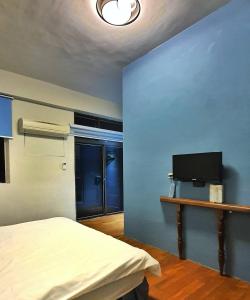 une chambre avec un lit et un mur bleu dans l'établissement 翼想旅宿-平價包棟民宿站前500m舒適便利-花蓮縣民宿2633號, à Hualien