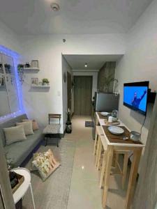 a living room with a table and a television at Cozy 1BR with balcony at Fame Residences in Manila