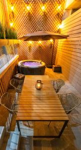 a wooden table and chairs on a patio with a hot tub at Lepanto Luxury Apartments GF in Nafpaktos