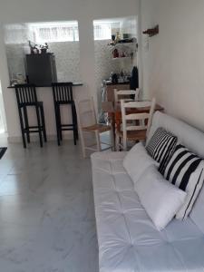 a living room with a white couch and chairs at Flat em Juquehy, 2 quartos, piscina e ar condicionado in São Sebastião
