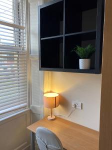 a desk with a lamp and a tv on a wall at 'Bloomfield' at stayBOOM in Lancaster