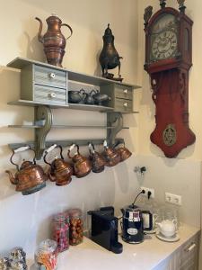 a clock and shelves with tea pots and pans at BnB 't Ambacht in Hendrik-Ido-Ambacht