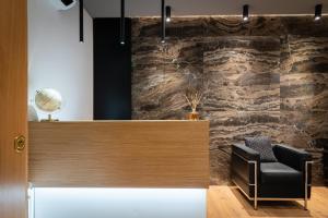 a chair in a lobby with a stone wall at Residenze Chamur- Grattacielo in Palermo