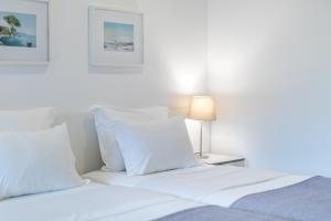 a bedroom with two beds with white pillows and a lamp at Hotel Baltum in Albufeira