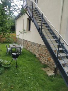 a patio with a grill and stairs next to a house at A la bon'Eure in Nassandres