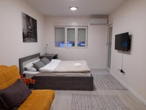 Apartment Diamond في بودغوريتسا: غرفة نوم بسريرين وتلفزيون وأريكة