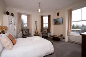 um quarto com uma grande cama branca e janelas em Wanslea Guest House em Ambleside