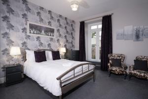 a bedroom with a bed and two chairs and a window at Wanslea Guest House in Ambleside