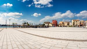 a large plaza with buildings and a blue sky with clouds at Welcomely - Isole Apartments in Olbia