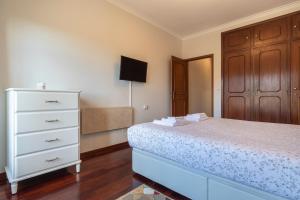 a bedroom with a white bed and a dresser at Casa Miha in Sintra