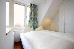 ein weißes Schlafzimmer mit einem Bett und einem Fenster in der Unterkunft Ferienvillen Anna Düne Ferienvillen Anna Düne 3-08 in Wangerooge