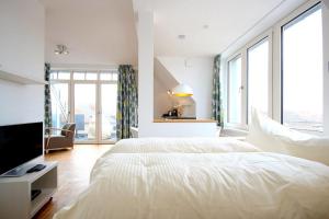 ein weißes Schlafzimmer mit einem großen Bett und großen Fenstern in der Unterkunft Ferienvillen Anna Düne Ferienvillen Anna Düne 3-08 in Wangerooge