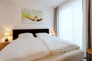 ein weißes Bett in einem Schlafzimmer mit einem Fenster in der Unterkunft DünenResort Binz DünenResort Binz 125 in Binz