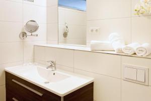 ein weißes Badezimmer mit Waschbecken und Spiegel in der Unterkunft DünenResort Binz DünenResort Binz 125 in Binz + 11 Fotos