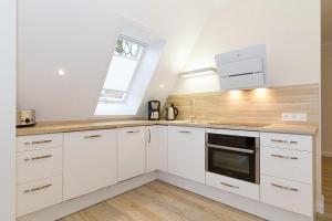 a kitchen with white cabinets and a sink and a window at Villa Löwenstein Villa Löwenstein 14 in Kühlungsborn