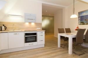 a kitchen with white cabinets and a table with chairs at Villa Löwenstein Villa Löwenstein 14 in Kühlungsborn +4 photos