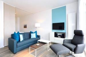 a living room with a blue couch and two chairs at Aparthotel Anna Düne Aparthotel Anna Düne 1-22 in Wangerooge