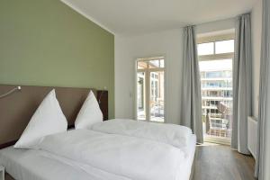 a bedroom with a bed with white sheets and a window at Aparthotel Anna Düne Aparthotel Anna Düne 2-39 in Wangerooge