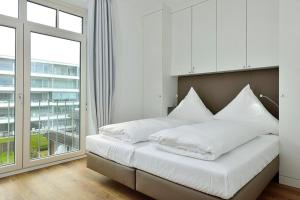 a bedroom with a bed with white sheets and a window at Aparthotel Anna Düne Aparthotel Anna Düne 2-38 in Wangerooge