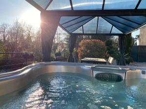 a hot tub in a backyard with a pergola at Les Rives des Habsbourg in Ensisheim