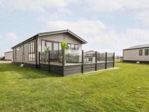 ein modulares Haus mit Glasfenstern und einem grünen Hof in der Unterkunft Summerdown in Burnham on Sea