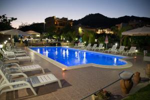 a swimming pool with white chairs and a pool at B&B Il Sole Nascente in Furci Siculo