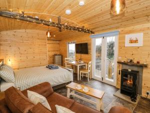 Dormitorio en cabaña de madera con cama y chimenea en Robins Nest, en Southam