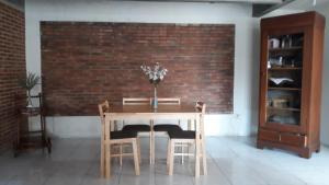 a dining room table with chairs and a brick wall at BRB Guesthouse in Banyuwangi