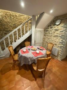 ein Esszimmer mit einem Tisch, Stühlen und einer Treppe in der Unterkunft Gîte Les Tilleuls in La Porcherie