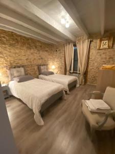 1 Schlafzimmer mit 2 Betten und einer Steinmauer in der Unterkunft Gîte Les Tilleuls in La Porcherie