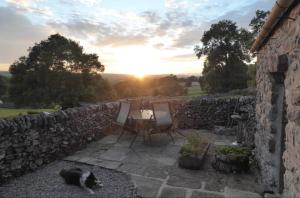 a cat walking on a patio with the sunset in the background at Cruck Cottage in Buxton