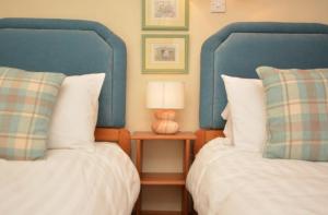 a bedroom with two beds and a table with a lamp at Cruck Cottage in Buxton