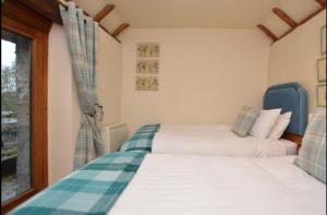 two beds in a room with a window at Cruck Cottage in Buxton +1 photo