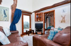a living room with a couch and a television at Cruck Cottage in Buxton