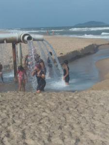 a group of people playing in the water on the beach at Paraíso dos Accácio in Balneario Barra do Sul