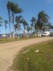 a dirt road next to a beach with palm trees at Paraíso dos Accácio in Balneario Barra do Sul