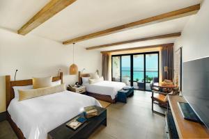 a bedroom with two beds and a flat screen tv at Unico Hotel Riviera Maya Adults Only in Akumal
