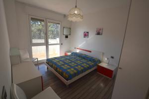 1 dormitorio con 1 cama, 1 silla y 1 ventana en Lignano, en Lignano Sabbiadoro