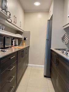 a kitchen with brown cabinets and a refrigerator at Apartamento VISTA Al RIO PUERTO SANTANA Riverfront 1 in Guayaquil