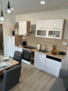 een keuken met witte kasten en een tafel met een eetkamer bij Apartman Ana in Crno
