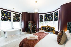 a bedroom with a bed and a tub and windows at Nydsley Hall by Maison Parfaite - 4 Luxury Apartments - 2 with Hot Tubs in Pateley Bridge