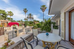 eine Terrasse mit einem Tisch, Stühlen und Palmen in der Unterkunft Villa con jardin cerca de la playa in Muro