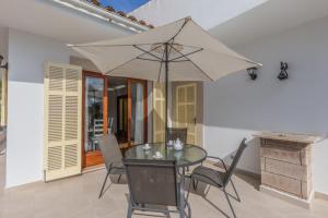 ein Esszimmer mit einem Glastisch und einem Sonnenschirm in der Unterkunft Villa con jardin cerca de la playa in Muro