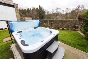 a bath tub sitting on a deck in a yard at Nydsley Hall by Maison Parfaite - 4 Luxury Apartments - 2 with Hot Tubs in Pateley Bridge