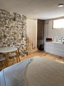 1 dormitorio con pared de piedra, mesa y cama en Ca la Vane en Cellers