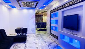 Habitación con TV y pared con luces azules. en شقة فخمة فيوالبحر Luxury Panorama Sea View, en Alejandría