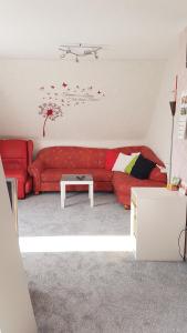 un soggiorno con un divano rosso e un tavolo di Ferienwohnung Kochel mit Wallbox a Gifhorn